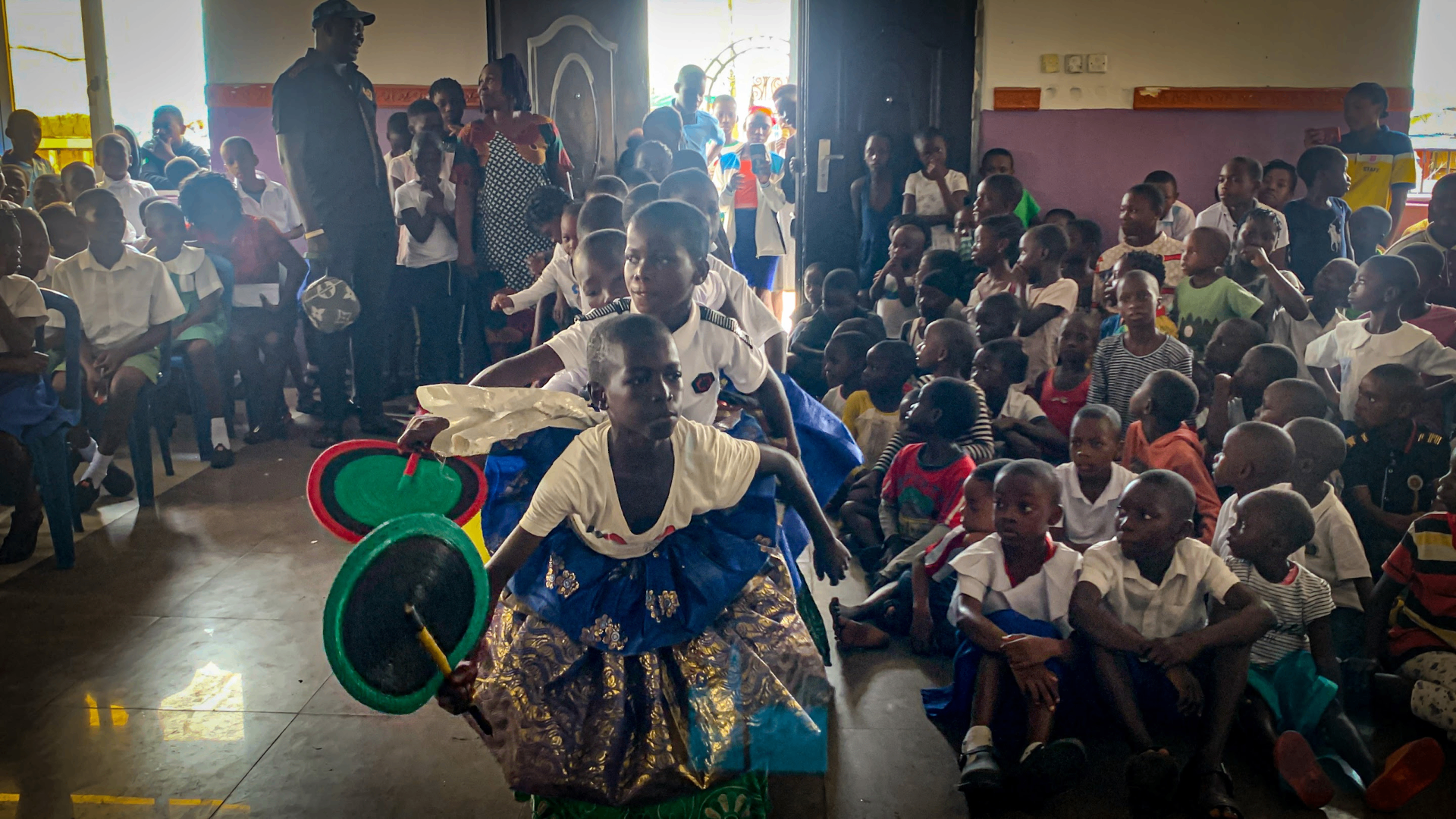 A young performer leading a dance before an audience of children at a YVEI event