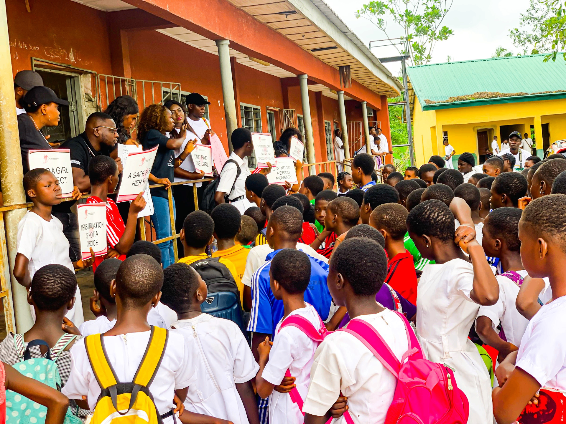 Students and YVEI participants holding Pad a Girl campaign placards during a school outreach